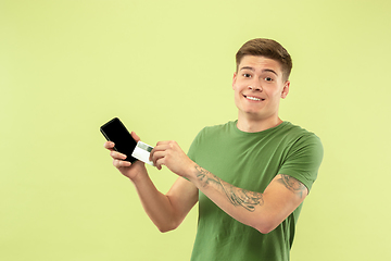 Image showing Caucasian young man\'s half-length portrait on green background