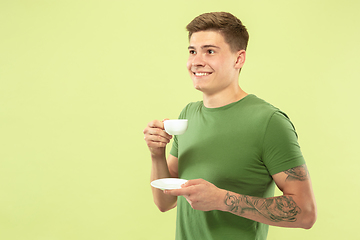 Image showing Caucasian young man\'s half-length portrait on green background