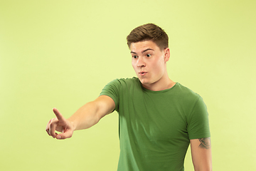 Image showing Caucasian young man\'s half-length portrait on green background