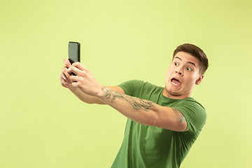 Image showing Caucasian young man\'s half-length portrait on green background