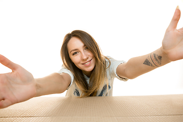 Image showing Young woman opening the biggest postal package isolated on white