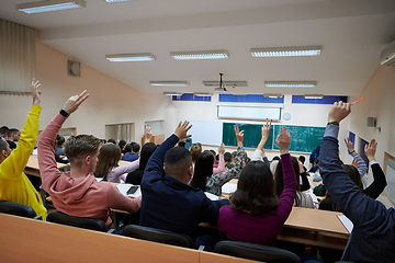 Image showing Raised hands and arms of large group of people in class room