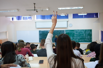 Image showing female student sitting in the class and raising hand up