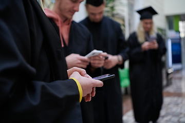 Image showing students in mortar boards using smartphone