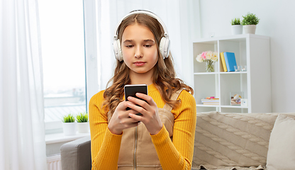 Image showing teenage girl in headphones with smartphone at home