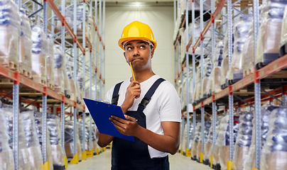 Image showing thinking indian worker with clipboard at warehouse