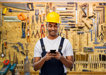 Image showing happy indian or builder in helmet using smartphone