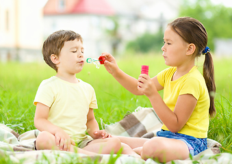 Image showing Little girl and boy are blowing soap bubbles