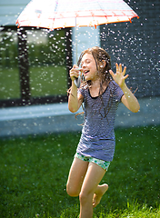 Image showing Happy girl is playing under rain