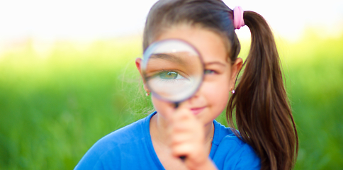 Image showing Little girl is looking through magnifier