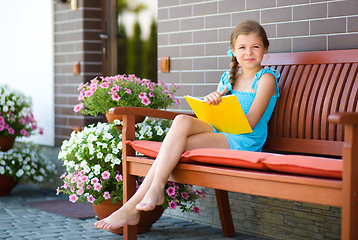 Image showing Little girl is reading a book