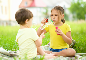 Image showing Little girl and boy are blowing soap bubbles