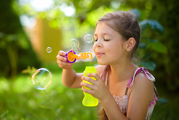 Image showing Little girl is blowing a soap bubbles