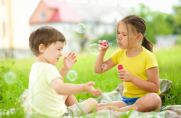 Image showing Little girl and boy are blowing soap bubbles