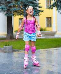 Image showing Happy little girl is skating on rollers