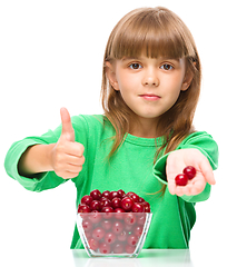 Image showing Cute girl is eating cherries showing thumb up sigh