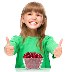 Image showing Cute girl is eating cherries showing thumb up sigh