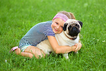 Image showing Little girl and her pug dog on green grass