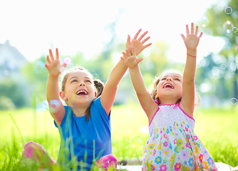 Image showing Two little girls are catching soap bubbles