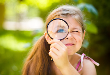 Image showing Little girl is looking through magnifier
