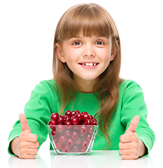 Image showing Cute girl is eating cherries showing thumb up sigh