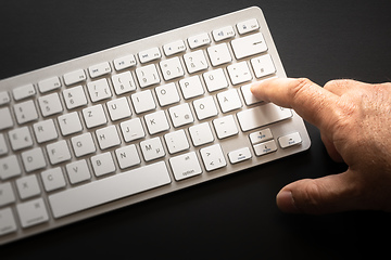 Image showing typical computer keyboard with finger on enter