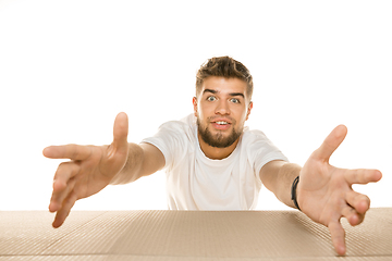 Image showing Young man opening the biggest postal package isolated on white