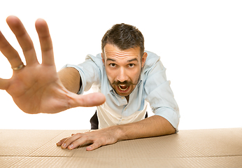 Image showing Young man opening the biggest postal package isolated on white