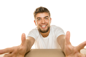 Image showing Young man opening the biggest postal package isolated on white