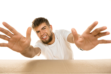 Image showing Young man opening the biggest postal package isolated on white