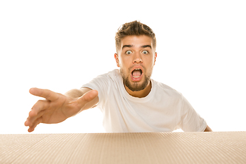 Image showing Young man opening the biggest postal package isolated on white