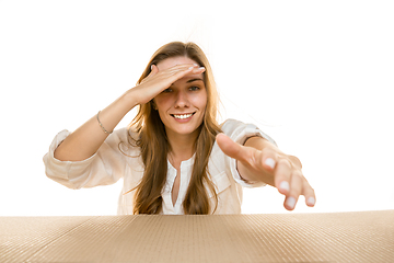 Image showing Young woman opening the biggest postal package isolated on white