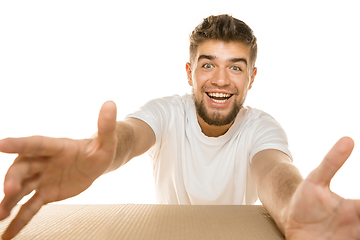 Image showing Young man opening the biggest postal package isolated on white