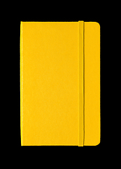 Image showing Yellow closed notebook isolated on black