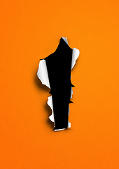 Image showing Orange torn paper with black hole