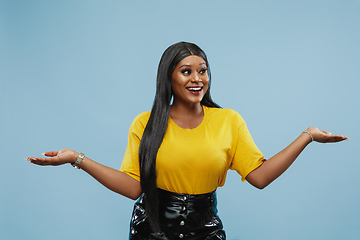 Image showing African-american young woman\'s half-length portrait on blue background