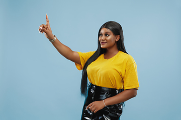 Image showing African-american young woman\'s half-length portrait on blue background