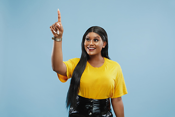 Image showing African-american young woman\'s half-length portrait on blue background