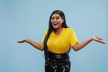 Image showing African-american young woman\'s half-length portrait on blue background