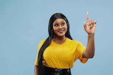 Image showing African-american young woman\'s half-length portrait on blue background