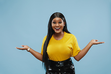 Image showing African-american young woman\'s half-length portrait on blue background