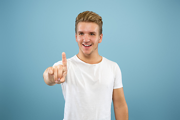 Image showing Caucasian young man\'s half-length portrait on blue background