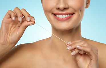 Image showing smiling woman with dental floss cleaning teeth