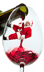 Image showing Happy Christmas Santa Claus climbing on trickle of wine on white background