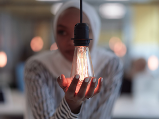 Image showing african american businesswoman holding hands around light bulb