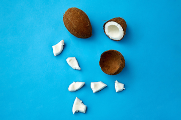 Image showing whole and cracked coconut on blue background