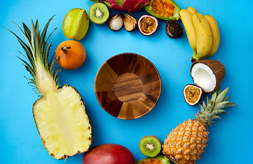 Image showing wooden bowl and different exotic fruits on blue