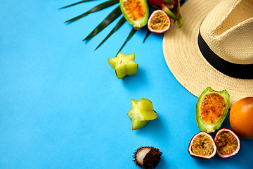 Image showing straw hat and exotic fruits on blue background