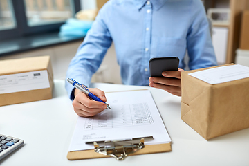 Image showing woman with smartphone and clipboard at post office