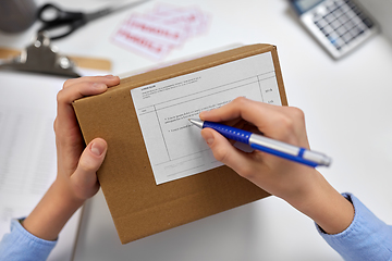 Image showing close up of hands filling form on parcel at office